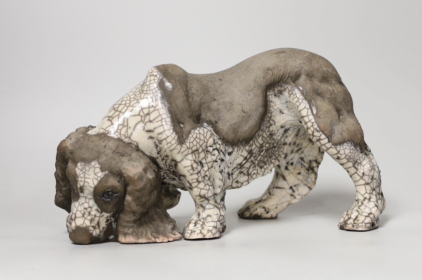 Keza Rudge (British 20th Century), a pottery model of a sniffing spaniel, signed. 29cm wide